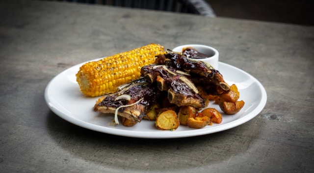 Grilled pork spare ribs, potato wedges with skin, corn, BBQ sauce 